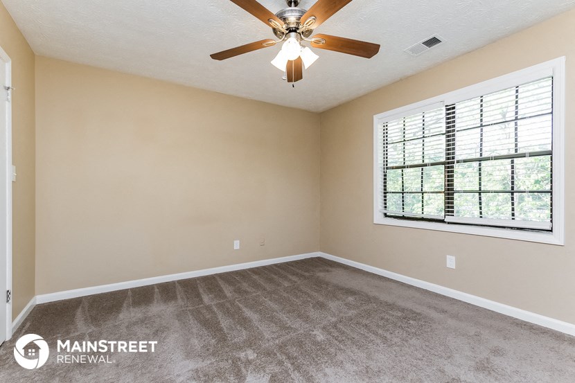 an empty living room with a ceiling fan and a large window