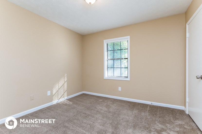 the spacious living room with carpeting and a window