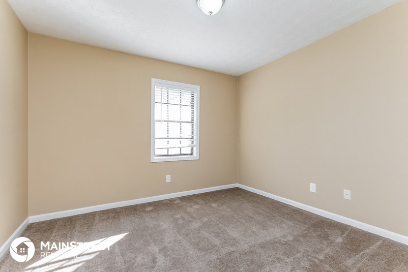 the spacious living room with carpeting and a window