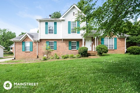 a brick and with green shutters and a lawn