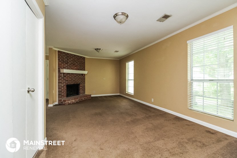a living room with a brick fireplace and a carpeted floor