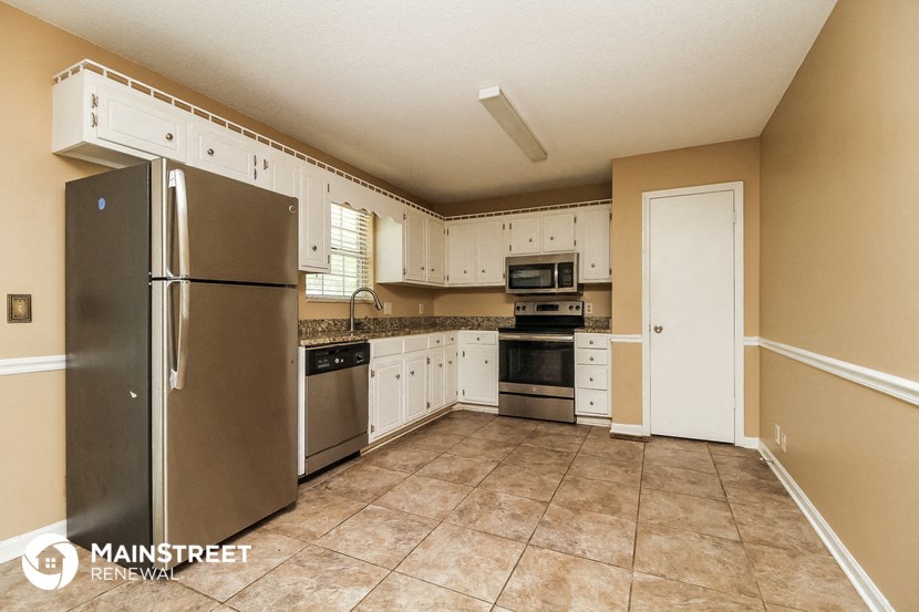 the kitchen has stainless steel appliances and white cabinets
