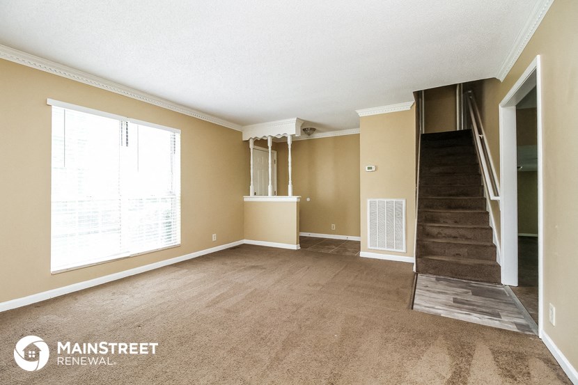 an empty living room with a staircase and a large window