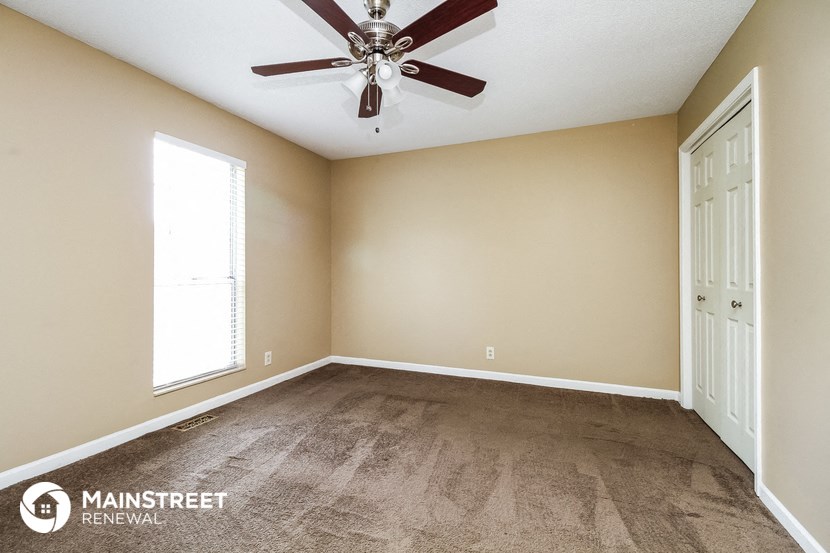 the master bedroom has a carpeted floor and a ceiling fan