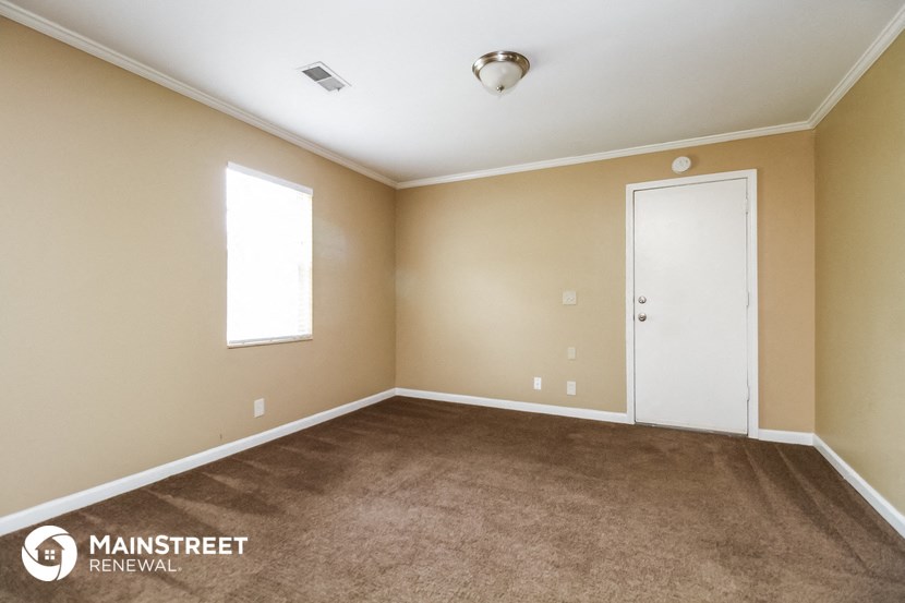a carpeted room with a white door and a window