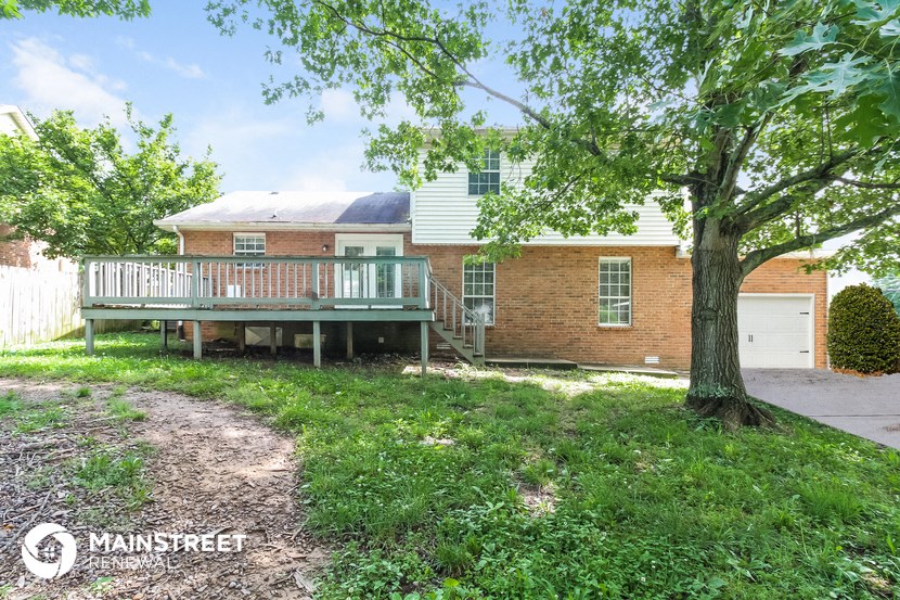 a house with a deck and a tree in front of it