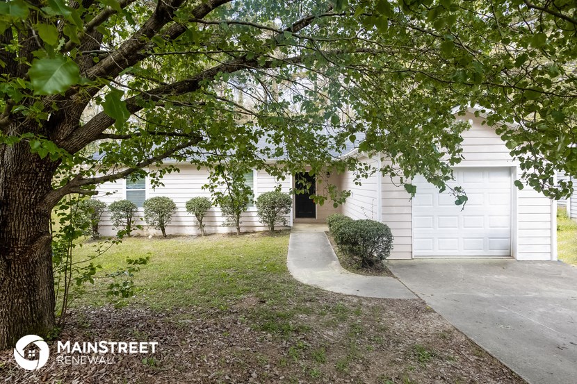 a white house with a garage door and a tree