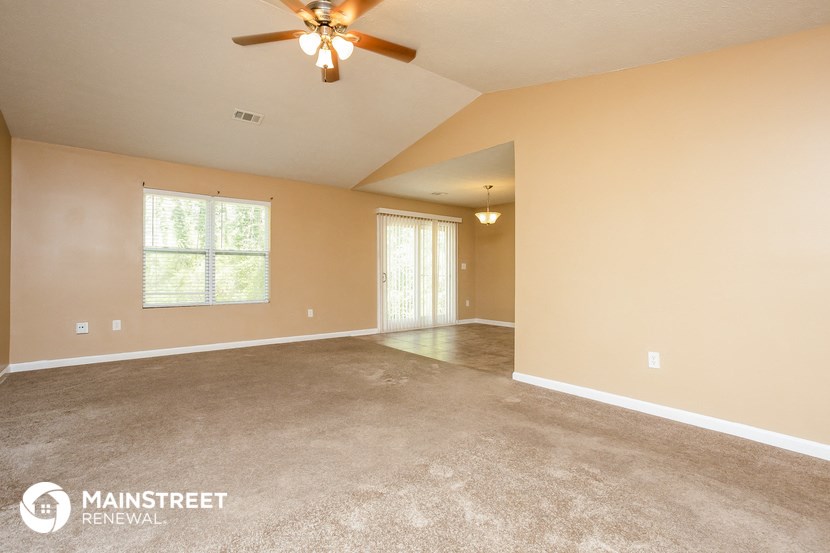 the living room of an empty house with a ceiling fan