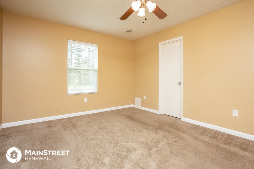 a carpeted room with a ceiling fan and a window