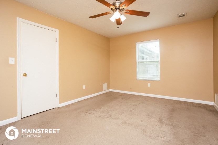 an empty living room with a ceiling fan and a white door