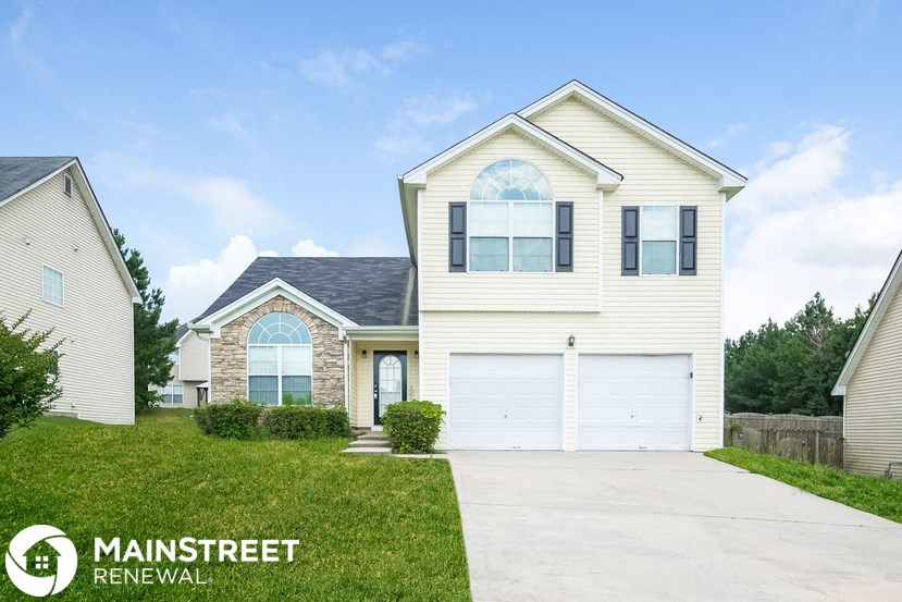 a white house with a garage door and a lawn
