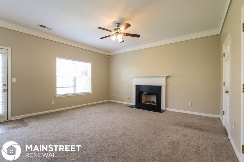 a living room with a fireplace and a ceiling fan