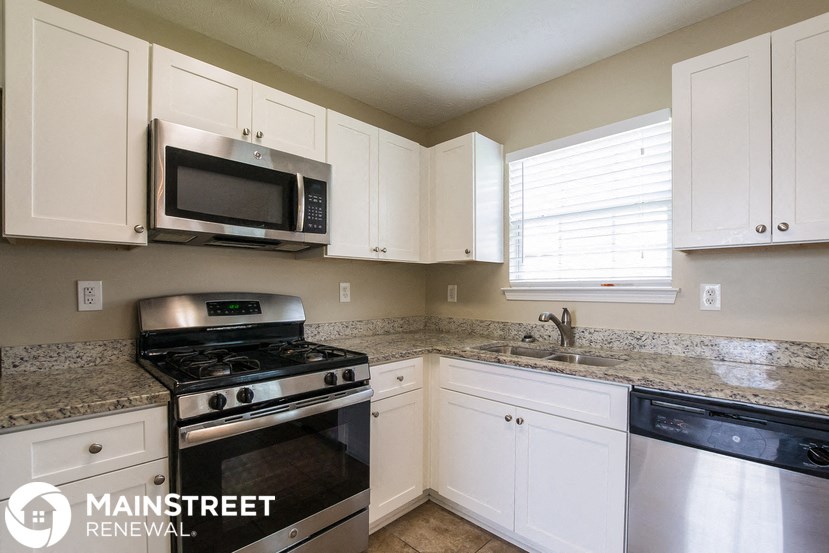 a kitchen with white cabinets and a stove and a microwave