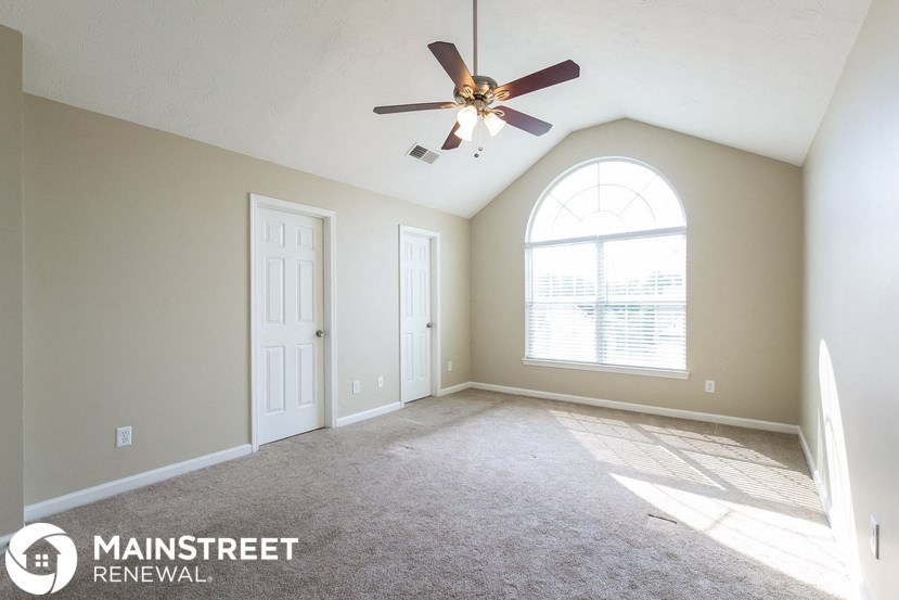 an empty living room with a ceiling fan and a large window