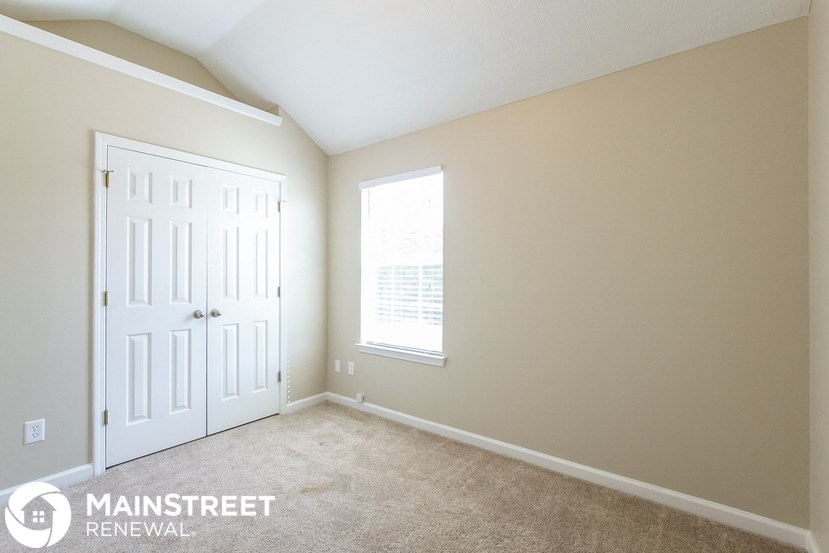 a bedroom with a door and a window and a carpeted floor