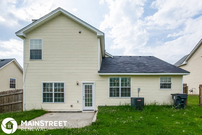 a white house with a black roof and a driveway