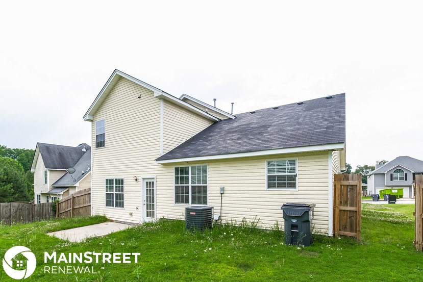 the front of a house with a yard and a wooden fence