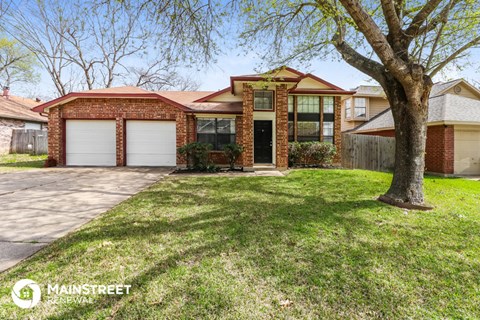 the front of a brick house with a yard and a tree