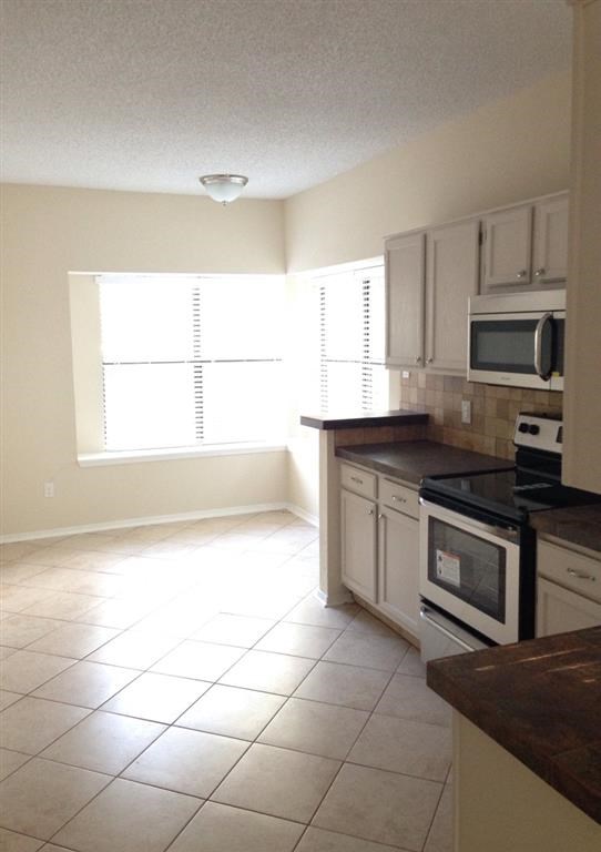 an empty kitchen with a stove and a microwave