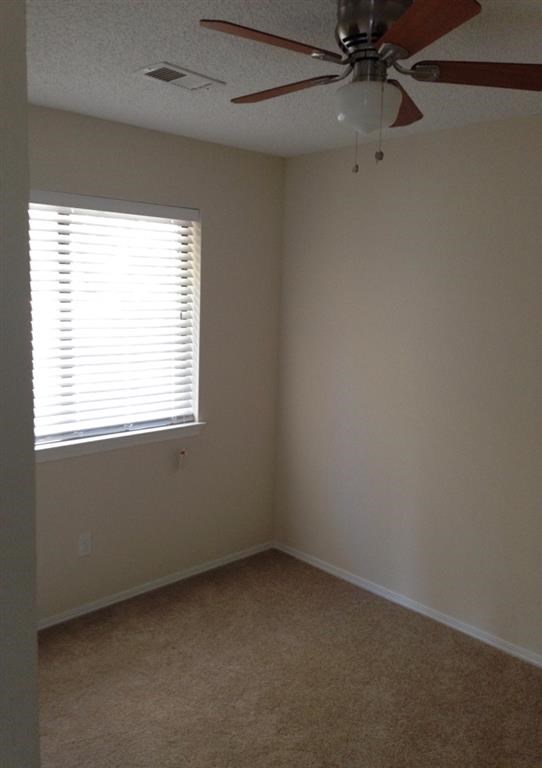 an empty room with a ceiling fan and a window