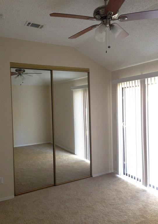 an empty living room with a ceiling fan and a mirrored closet