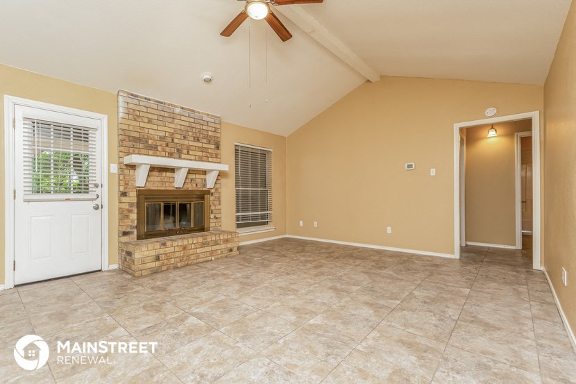 an empty living room with a brick fireplace and tile flooring