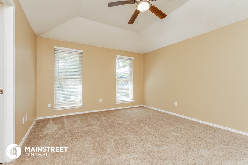 the master bedroom has a carpeted floor and a ceiling fan