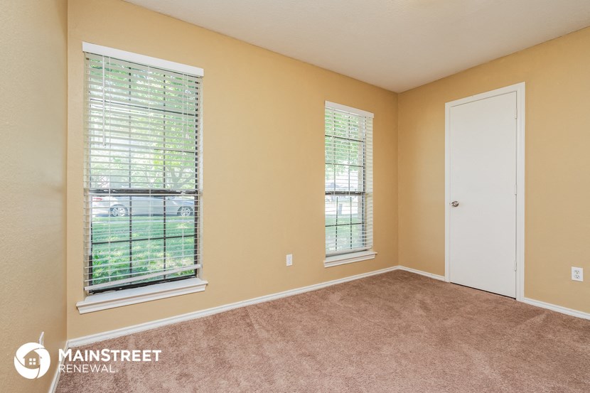 the master bedroom has a large window and carpeted flooring