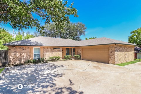 a brick house with a driveway and a tree