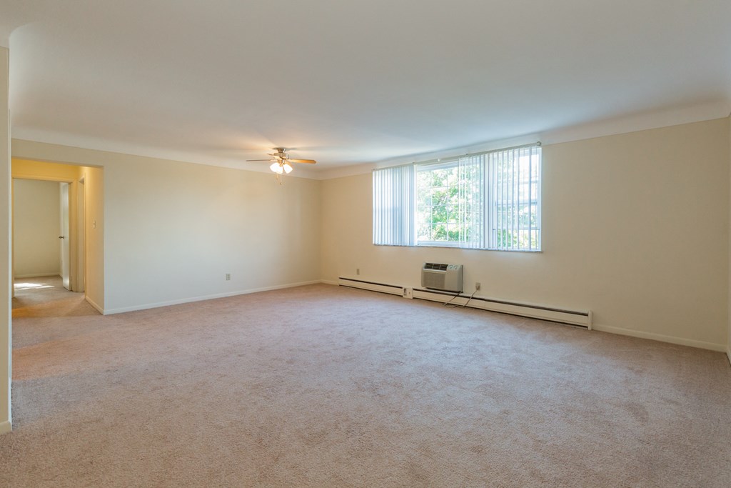 an empty living room with a window and a ceiling fan