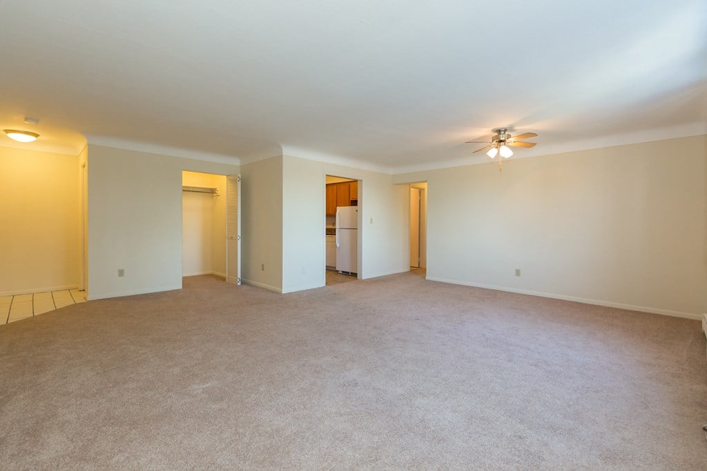 an empty living room with white walls and a ceiling fan