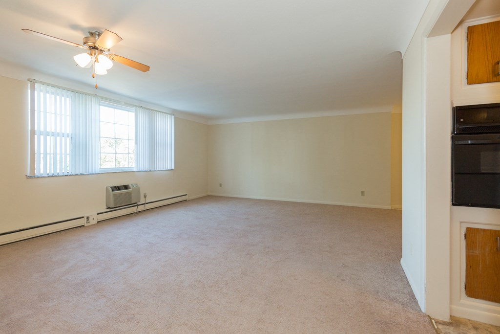 an empty living room with a ceiling fan and a window
