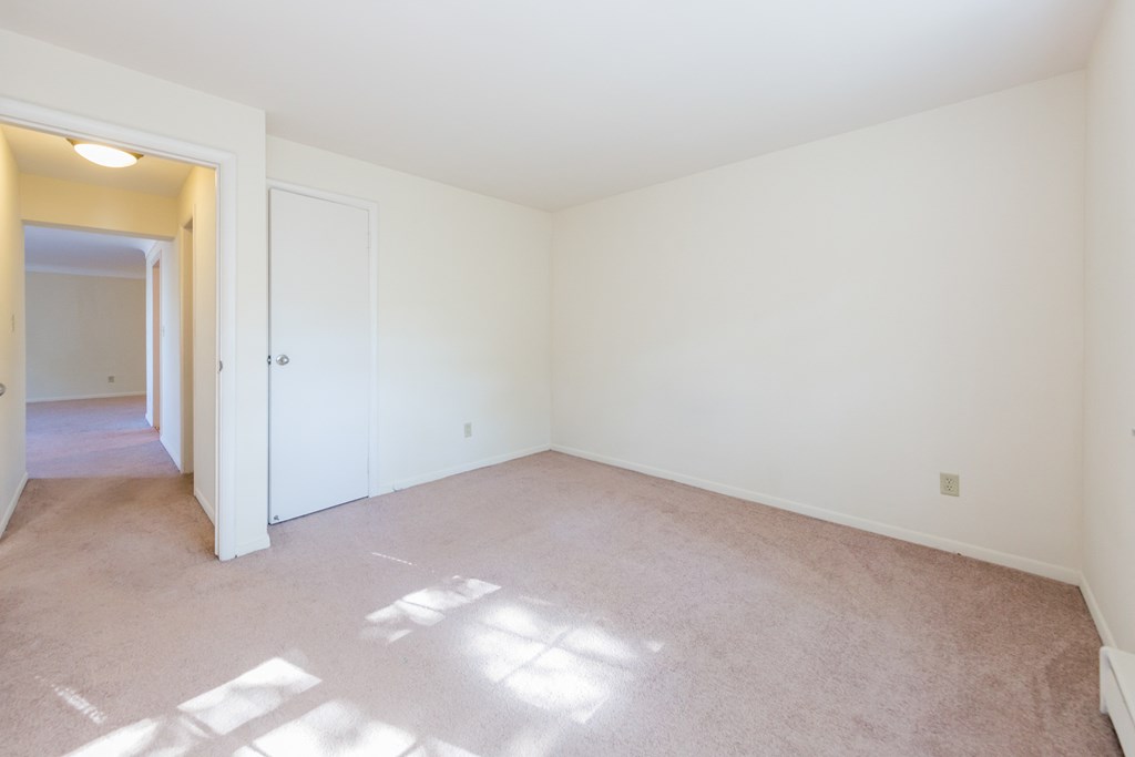 an empty living room with white walls and carpet