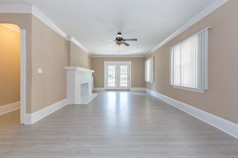 an empty living room with a ceiling fan and a fireplace