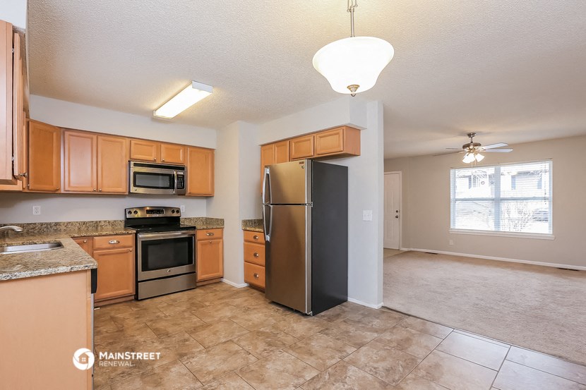 an empty kitchen with stainless steel appliances and wooden cabinets