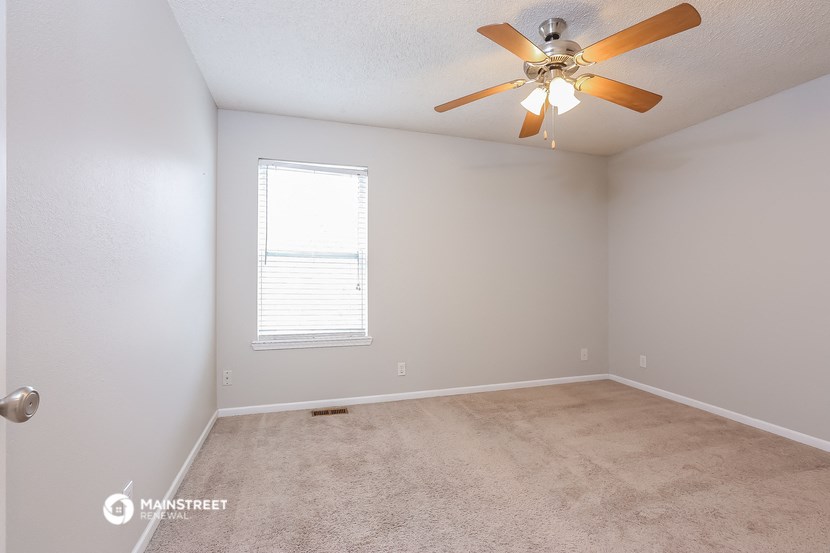 the spacious living room with ceiling fan and carpet