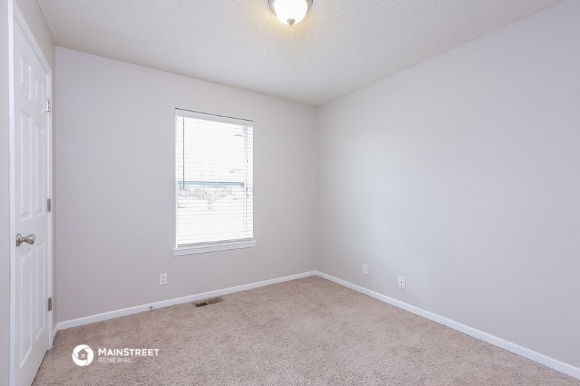 a bedroom with white walls and a window