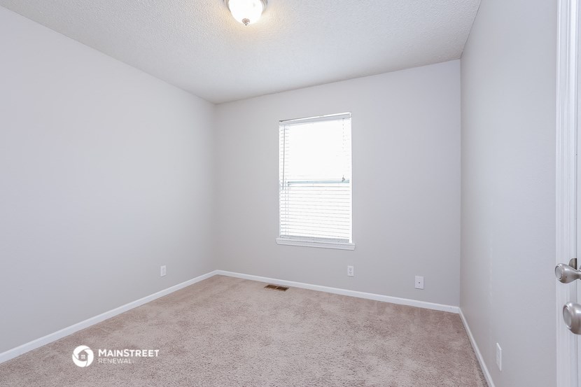 a bedroom with white walls and carpet and a window
