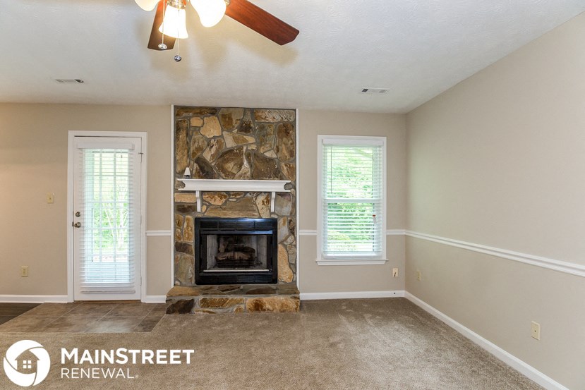a living room with a fireplace and a ceiling fan