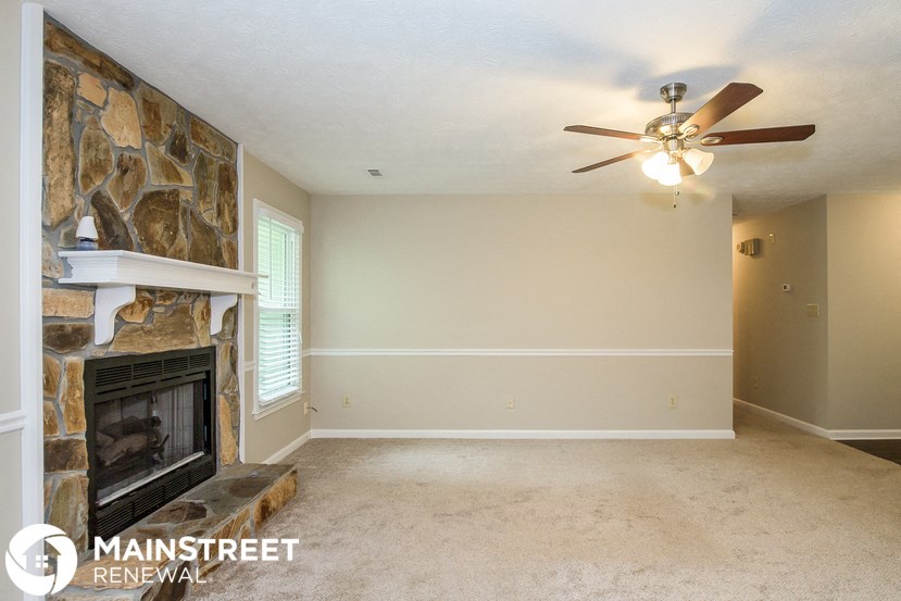 a living room with a fireplace and a ceiling fan