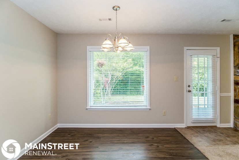 an empty living room with a window and a chandelier