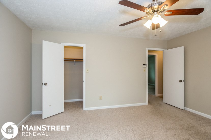 a bedroom with a ceiling fan and a closet