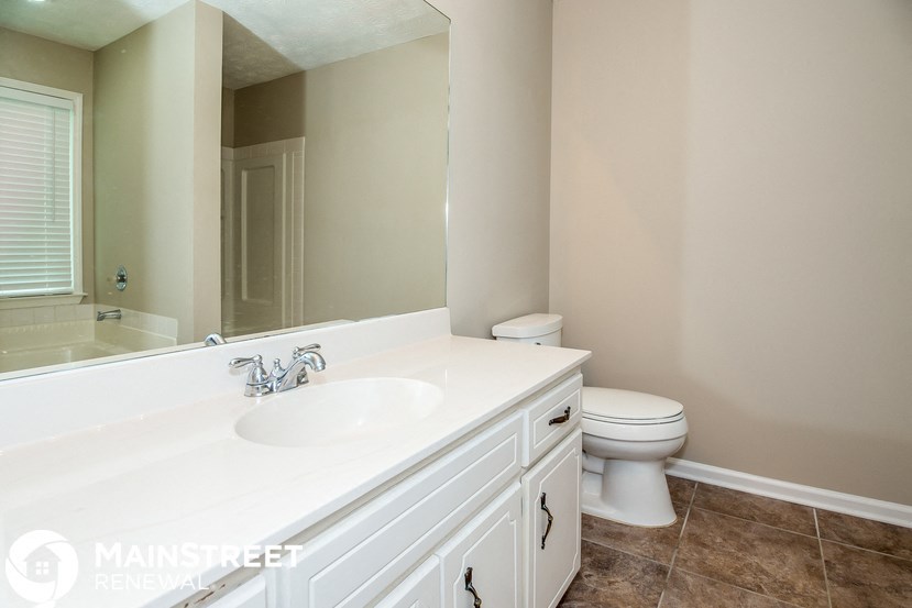a bathroom with a large mirror and a sink and a toilet