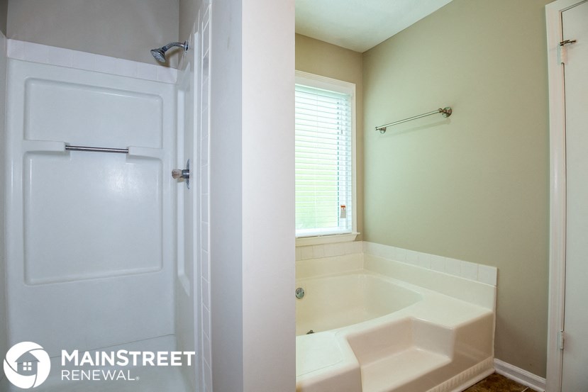 a bathroom with a tub and a shower and a white door