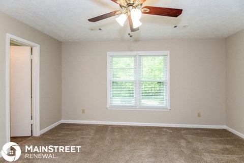a living room with carpet and a ceiling fan