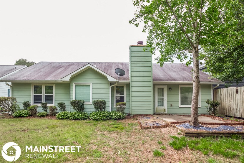 a green house with a yard and a tree