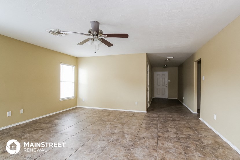 an empty living room with a ceiling fan and tile floor