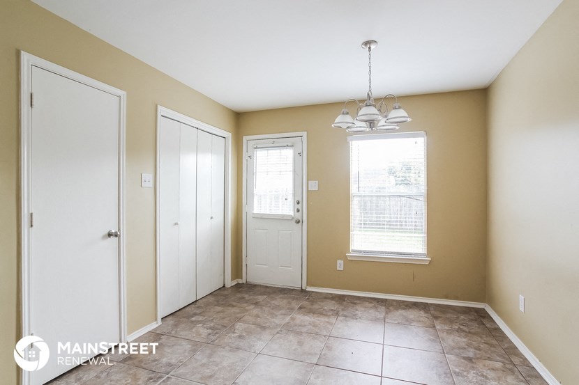 an empty dining room with two doors and a window