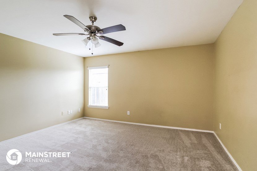 the spacious living room with ceiling fan and carpet