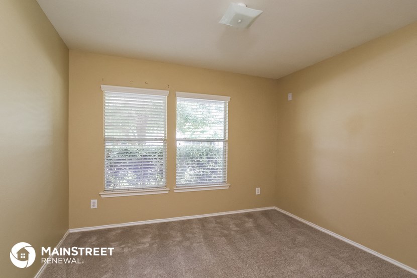 an empty room with two windows and a carpeted floor